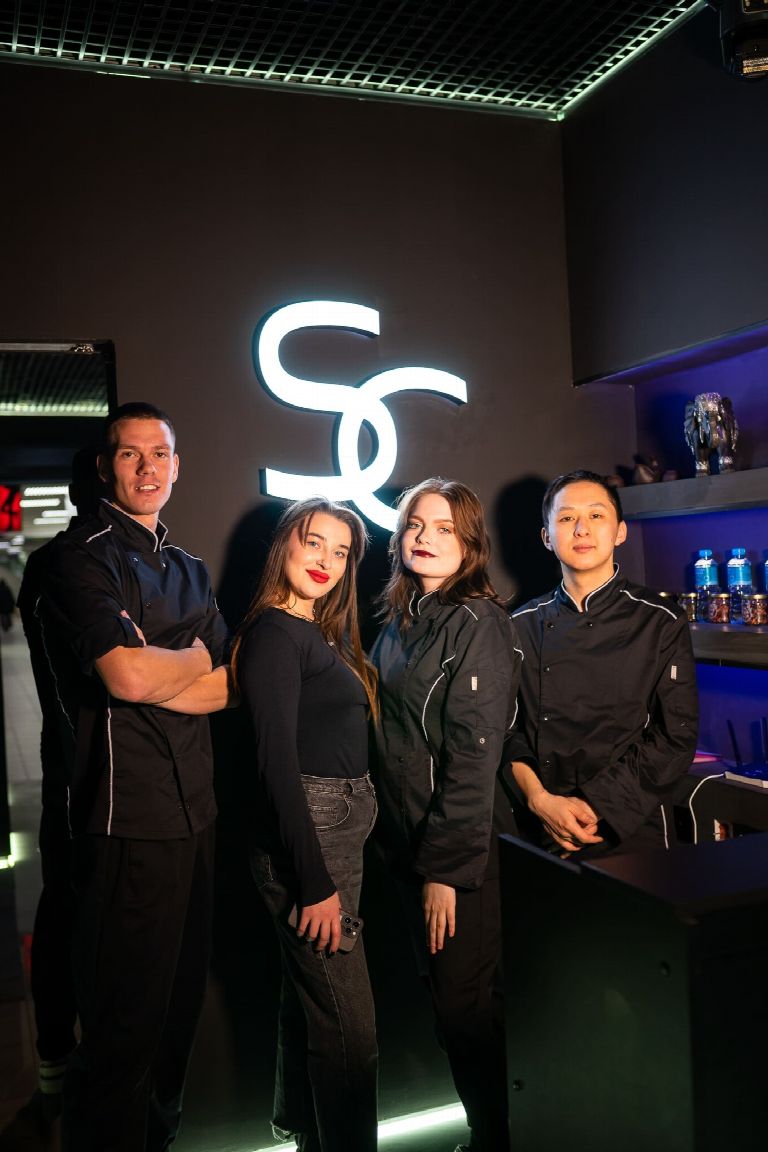 Команда SPA CITY у светящегося логотипа студии